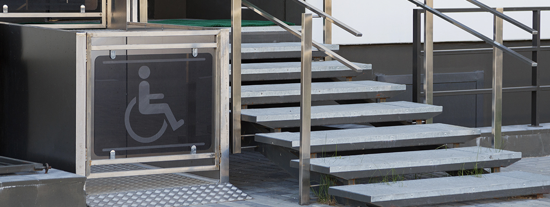 An accessible wheelchair lift sits adjacent to a set of stairs.
