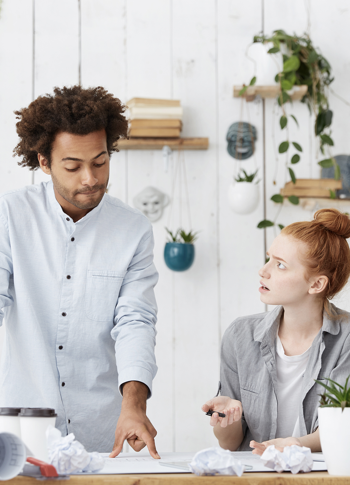 African American male and young red-headed female having an argument in a creative workplace.