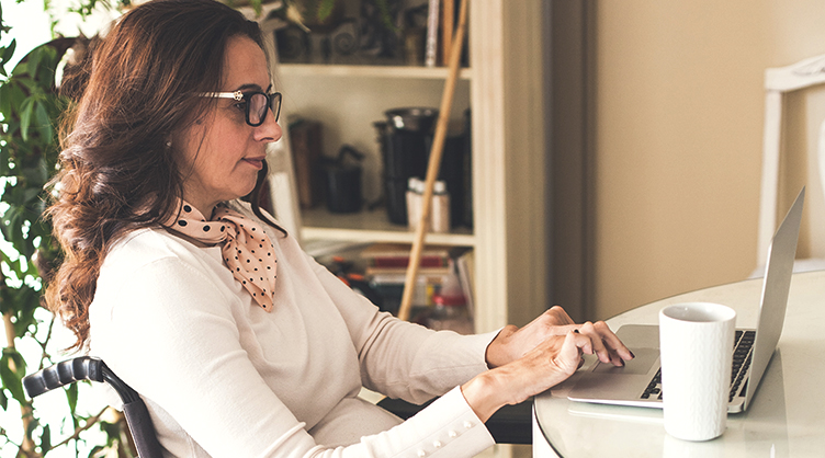 Middle aged woman who uses a power wheelchair working on her laptop computer.