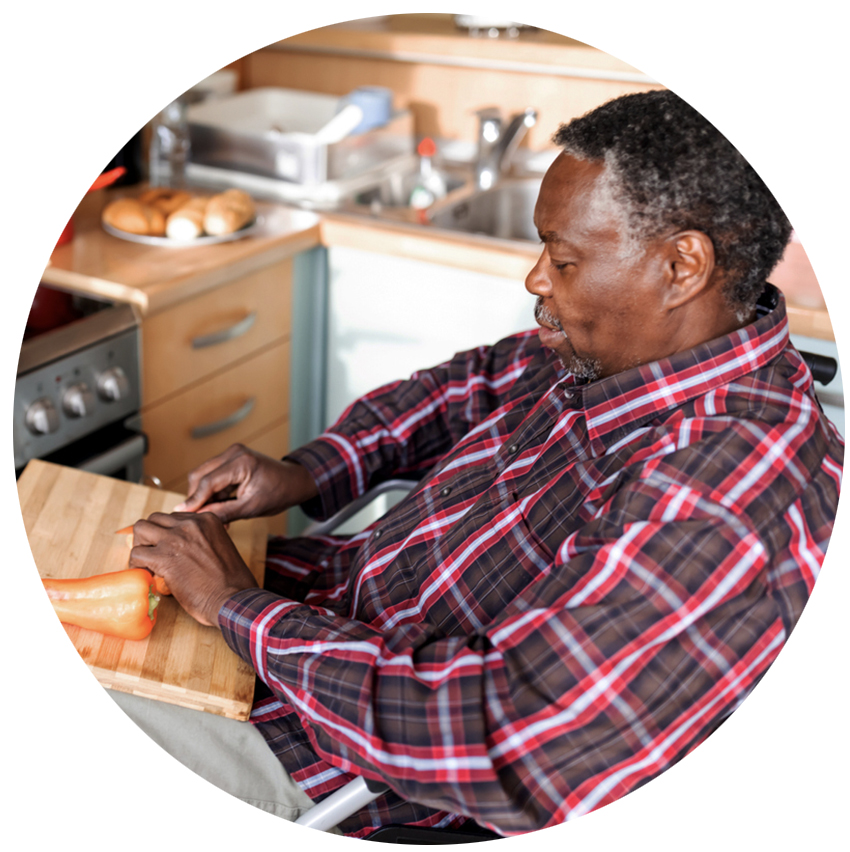 Elderly man in a wheelchair chopping vegetables.