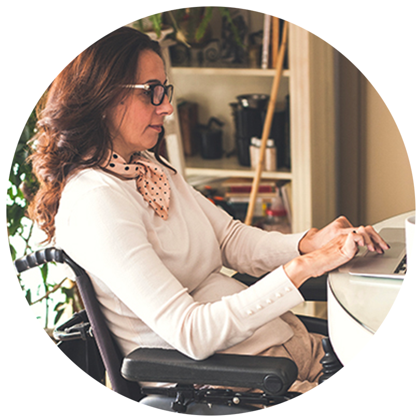 Middle aged woman who uses a power wheelchair working on her laptop computer.